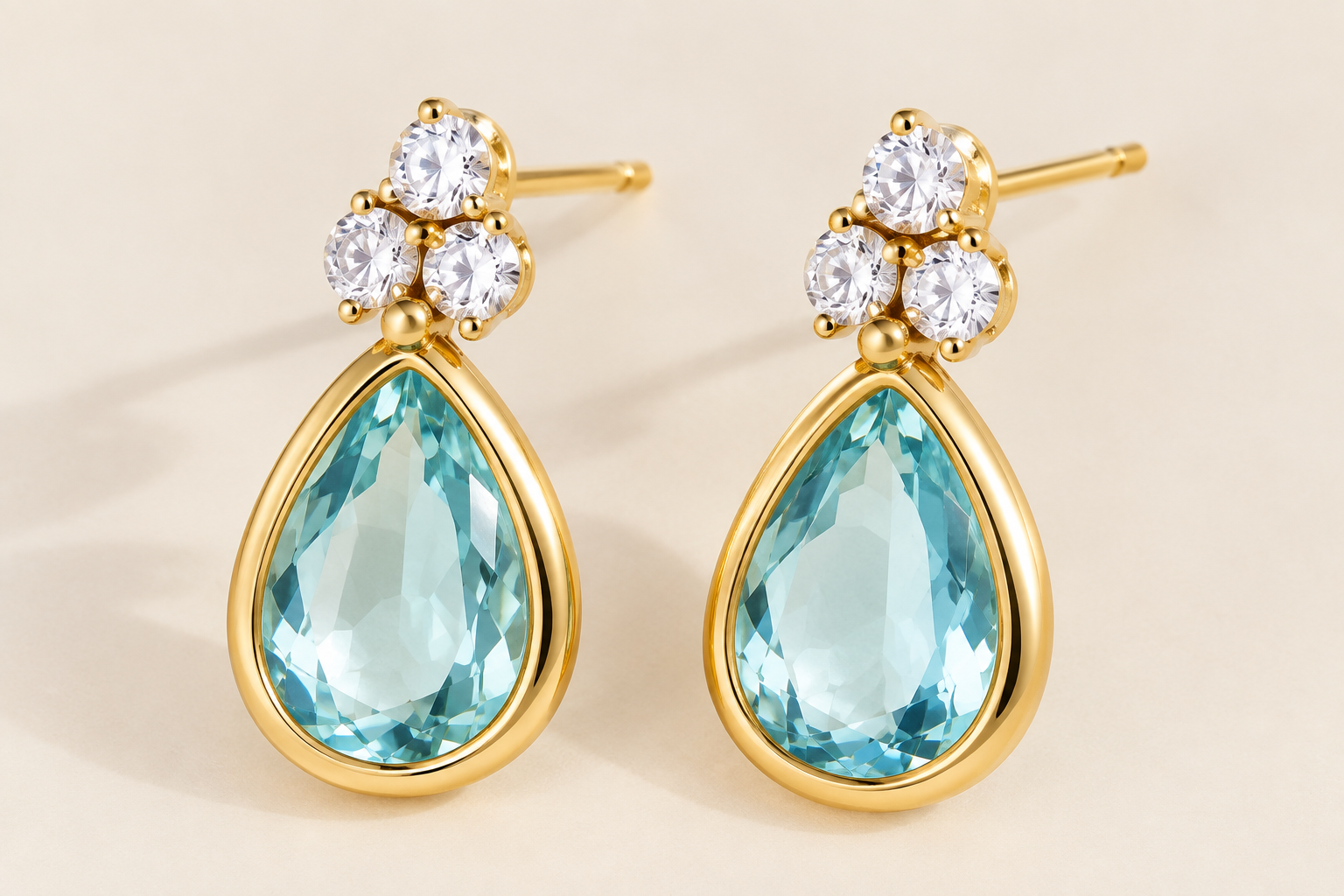 Diseño dorados con cristal azul en forma de lágrima y circones superiores.